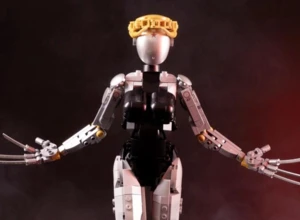 Робот с короной на голове, поднимающий руки, на фоне дымного темного окружения.