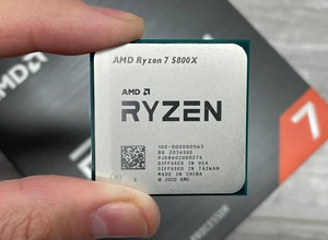 Процессор AMD Ryzen 7 580X в руке, на фоне упаковки.