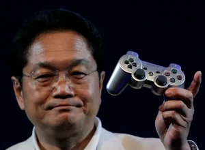 Человек в белом пиджаке держит в руке игровую консоль PlayStation.