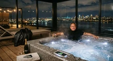 Человек в шортах расслабляется в джакузи с видом на ночной город.