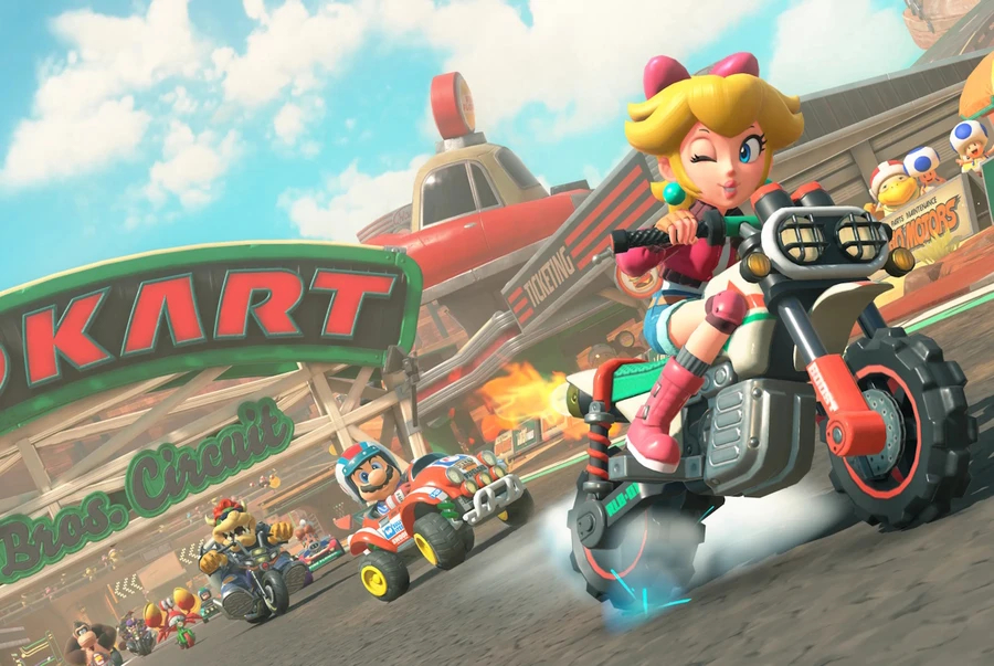 Персонаж в розовом костюме едет на мотоцикле по трассе с другими гонщиками.