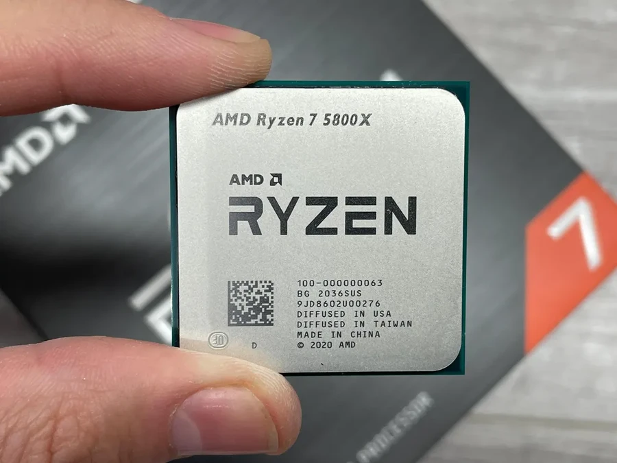 Процессор AMD Ryzen 7 580X в руке, на фоне упаковки.