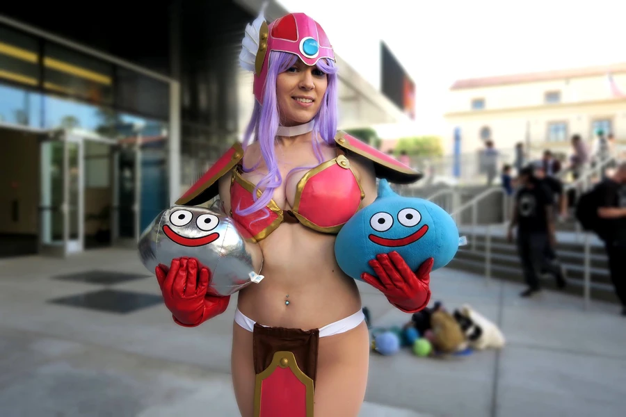 Женщина в костюме с фиолетовыми волосами, держащая игрушки с улыбающимися лицами.