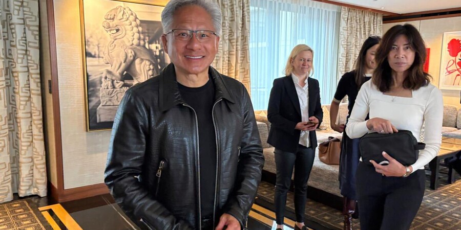 На фоне интерьера с картинами группа людей, один мужчина с улыбкой в кожаной куртке.