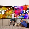 Два больших телевизора с техниками Sony и TCL, рядом стоят люди и собаки.