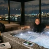 Человек в шортах расслабляется в джакузи с видом на ночной город.