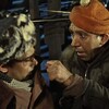 Два человека в теплой одежде, обсуждают что-то с напряжением на лицах.